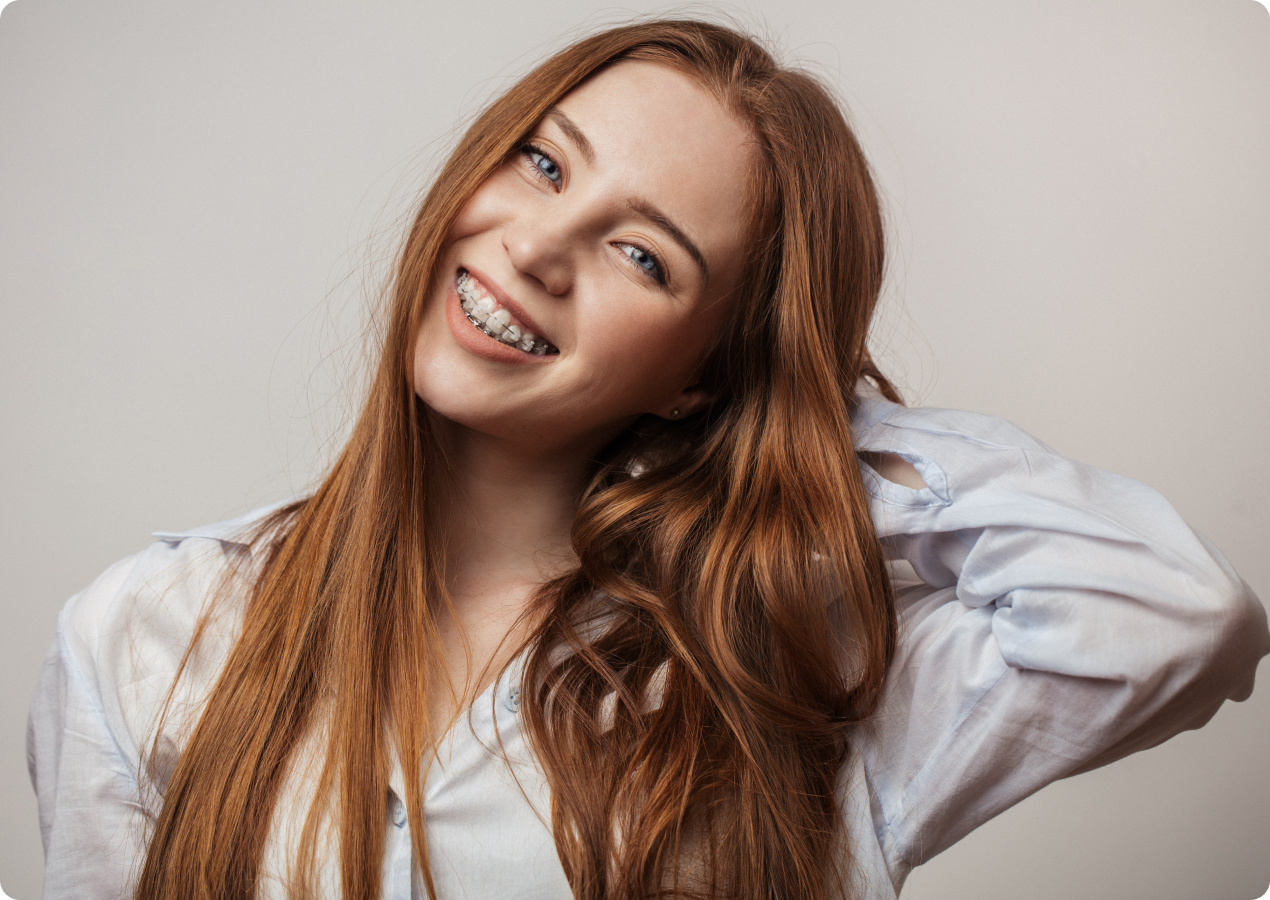 Jeune femme aux cheveux bouclés souriant avec un appareil dentaire