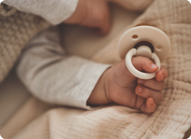 Main d'un bébé tenant une sucette