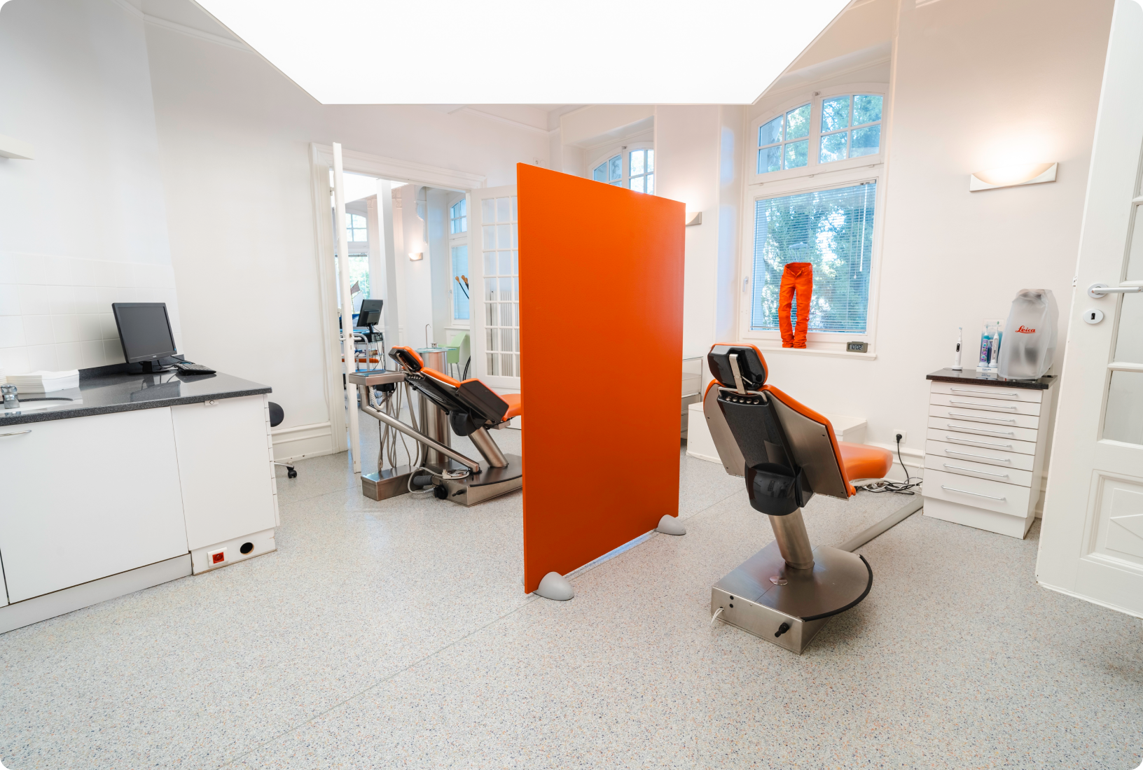 Salle de soin avec cloison orange et fauteuil dentaire