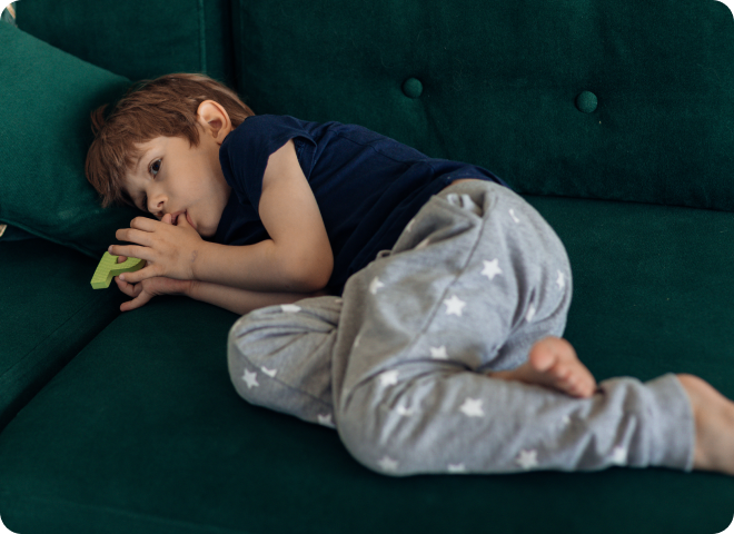 Enfant allongé suçant son pouce sur un canapé