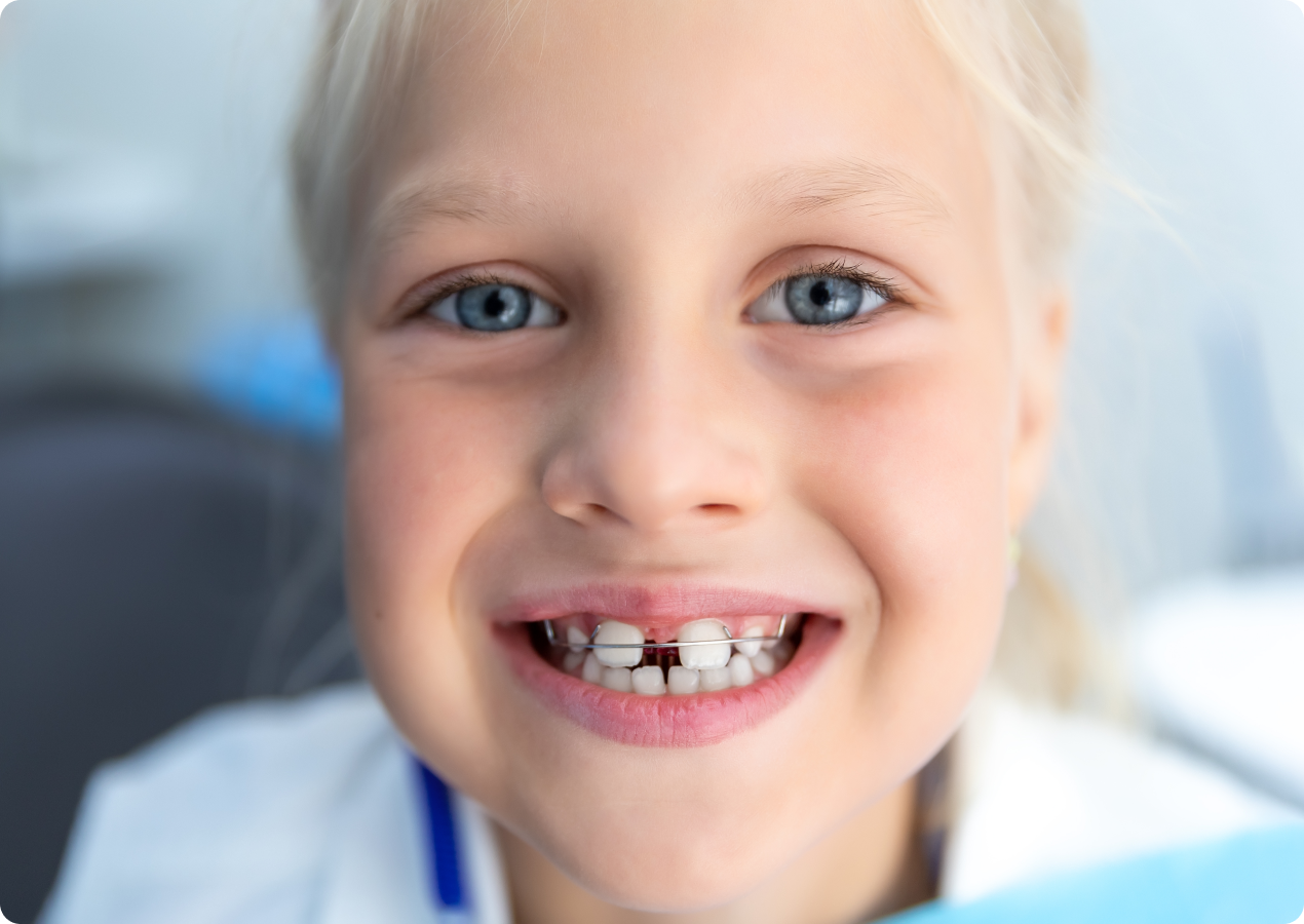 Petite fille souriante montrant ses dents en fauteuil dentaire