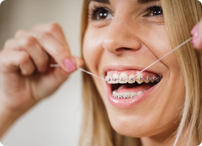 Femme souriante utilisant du fil dentaire avec des bagues